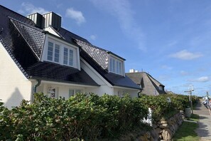 A row of white houses with dark roofs, a stone wall, and a clear sky. - Holiday home with 2 bedrooms (Wenningstedt)