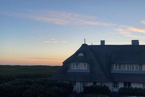 Ein Haus mit einem steilen Satteldach und einer kleinen Veranda.