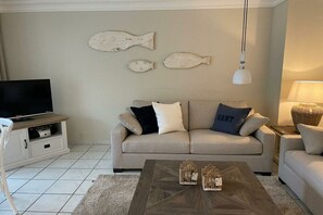 Ein Wohnzimmer mit einer Couch, einem Couchtisch und Wandverzierungen mit Fischmotiven.