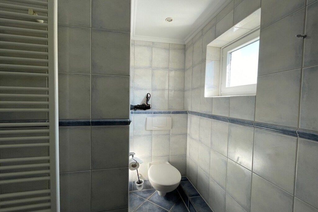 Ein Badezimmer mit Toilette, Fenster und Handtuchhalter.