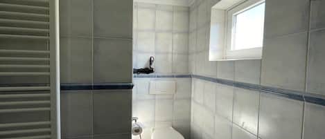 A bathroom with a toilet, a window, and a towel rack.