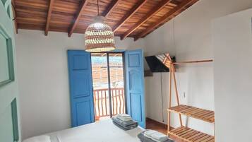 A bedroom with a wooden ceiling, a bed with white linens, a hanging light fixture, and a blue door.