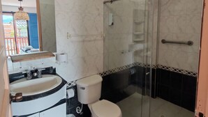 Un baño con inodoro, lavabo y zona de ducha.
