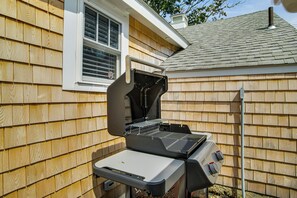 Un jardin avec un barbecue, un revêtement en bois et une fenêtre.