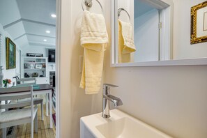 Een badkamer met een witte wastafel, een chromen kraan en twee handdoeken aan een handdoekhouder.