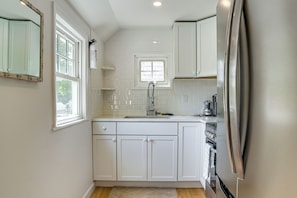 A modern kitchen with white cabinetry, a stainless steel refrigerator, and a window above the sink. - 3 Mi to Craigville Beach! Walkable Couple’s Haven (Osterville)