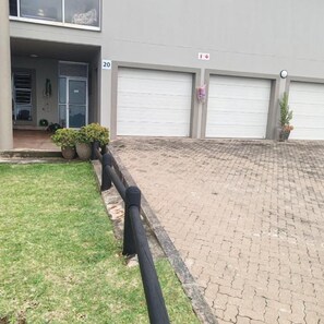 A building with a paved driveway, a garage door, and a number sign indicating the unit number. - Alomsee 20 Ramsgate 4 bedroom apartment (Margate)