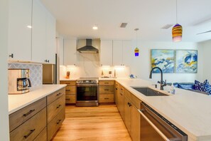 A modern kitchen with wooden cabinets, a built-in oven, and a large island with a sink. - Steps to Blue Mountain Beach! 30A Getaway w/ Deck (Santa Rosa Beach)