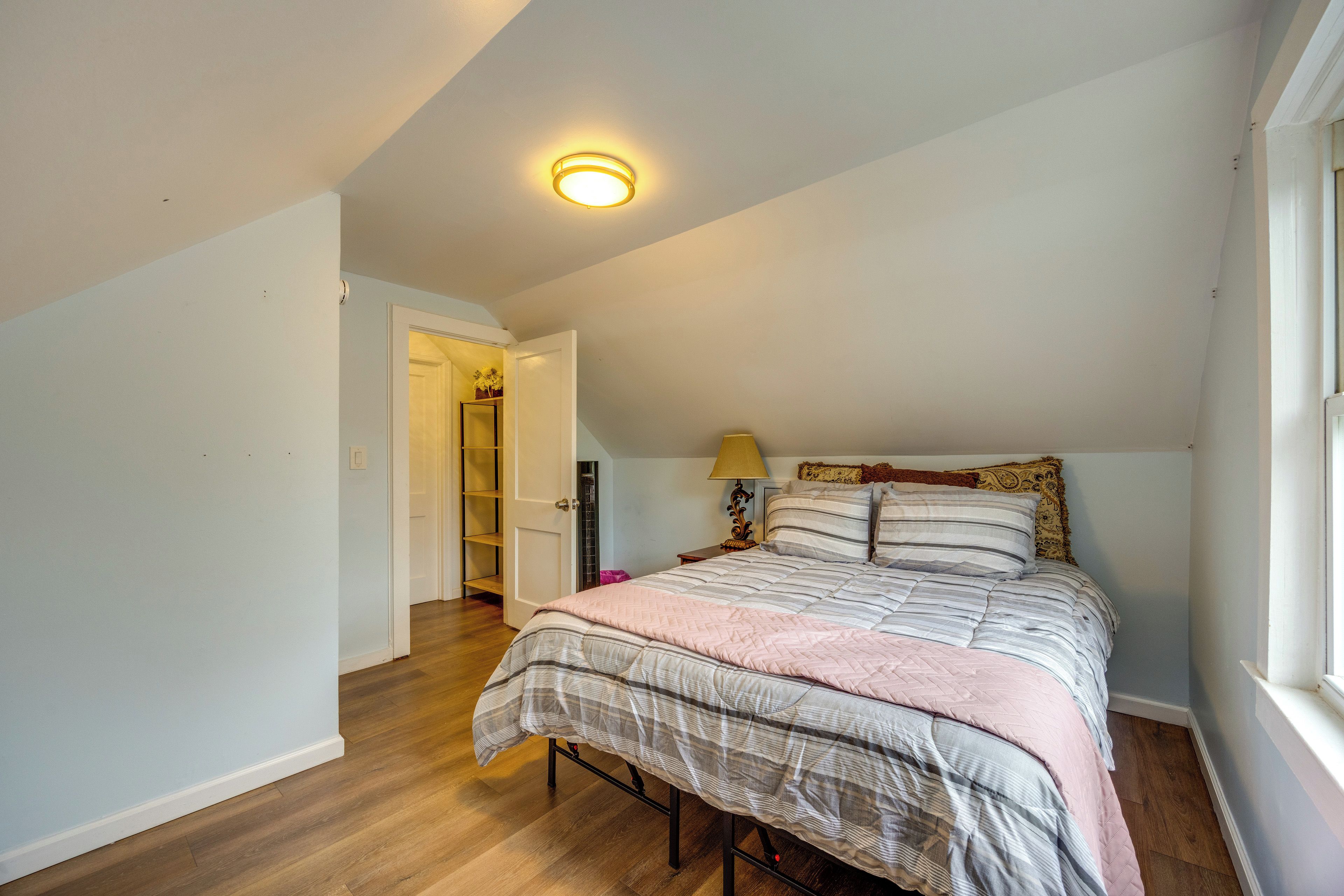 Une chambre à coucher avec un lit, une table de chevet, une lampe et une fenêtre.