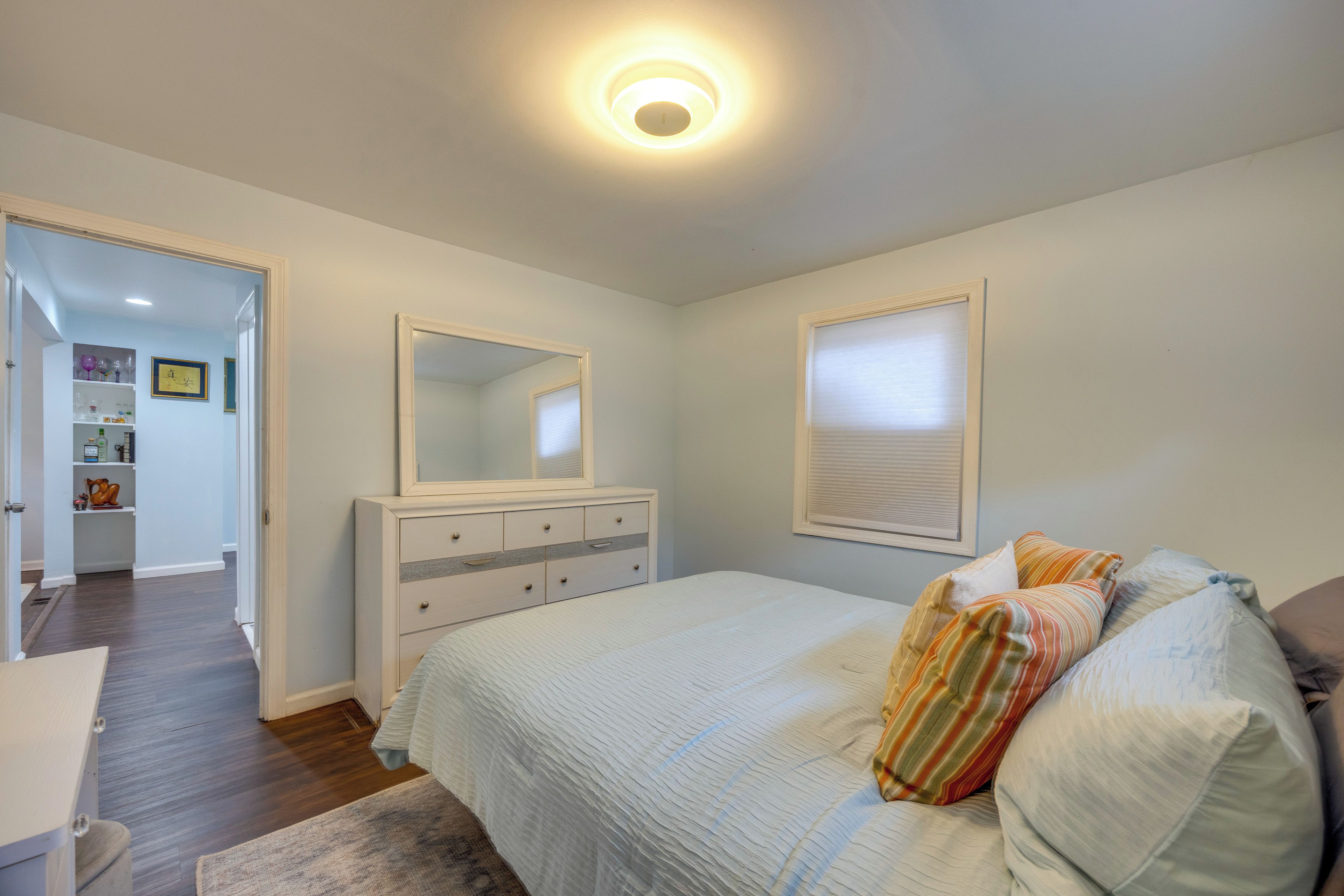 Ein Schlafzimmer mit Bett, Schminktisch, Spiegel und einer Tür zu einem Badezimmer.