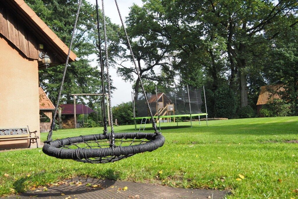 Eine Hängeschaukel in einem grünen Garten mit einem Holzhaus und einer Bank im Hintergrund.