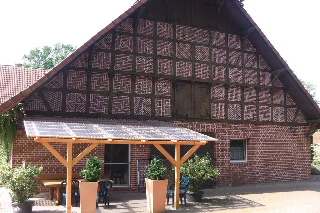 Ein traditionelles Fachwerkhäuschen mit einer Holzpergola und Topfpflanzen.