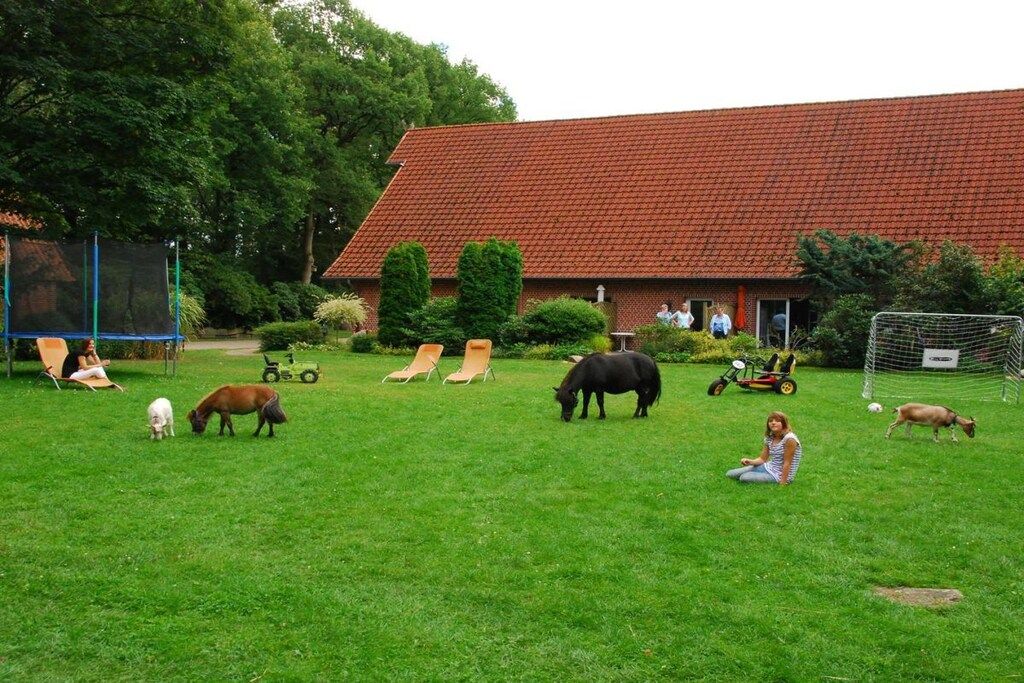 Een gazon met een gebouw op de achtergrond, een voetbaldoel en mensen die op stoelen zitten.