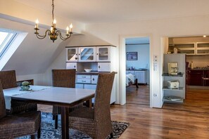 A dining area with a table, chairs, and a chandelier. There is a kitchen in the background with cabinets and a countertop. - Holiday apartment with 2 bedrooms (Rheinau-Holzhausen)