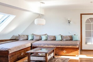 A cozy loft bedroom with a sloped ceiling, a wooden sofa bed, a glass coffee table, and a large window providing natural light. - Holiday apartment with 2 bedrooms (Rheinau-Holzhausen)
