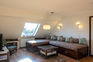 A cozy loft bedroom with a large window, a sofa bed, a television, and a small table. - Holiday apartment with 2 bedrooms (Rheinau-Holzhausen)