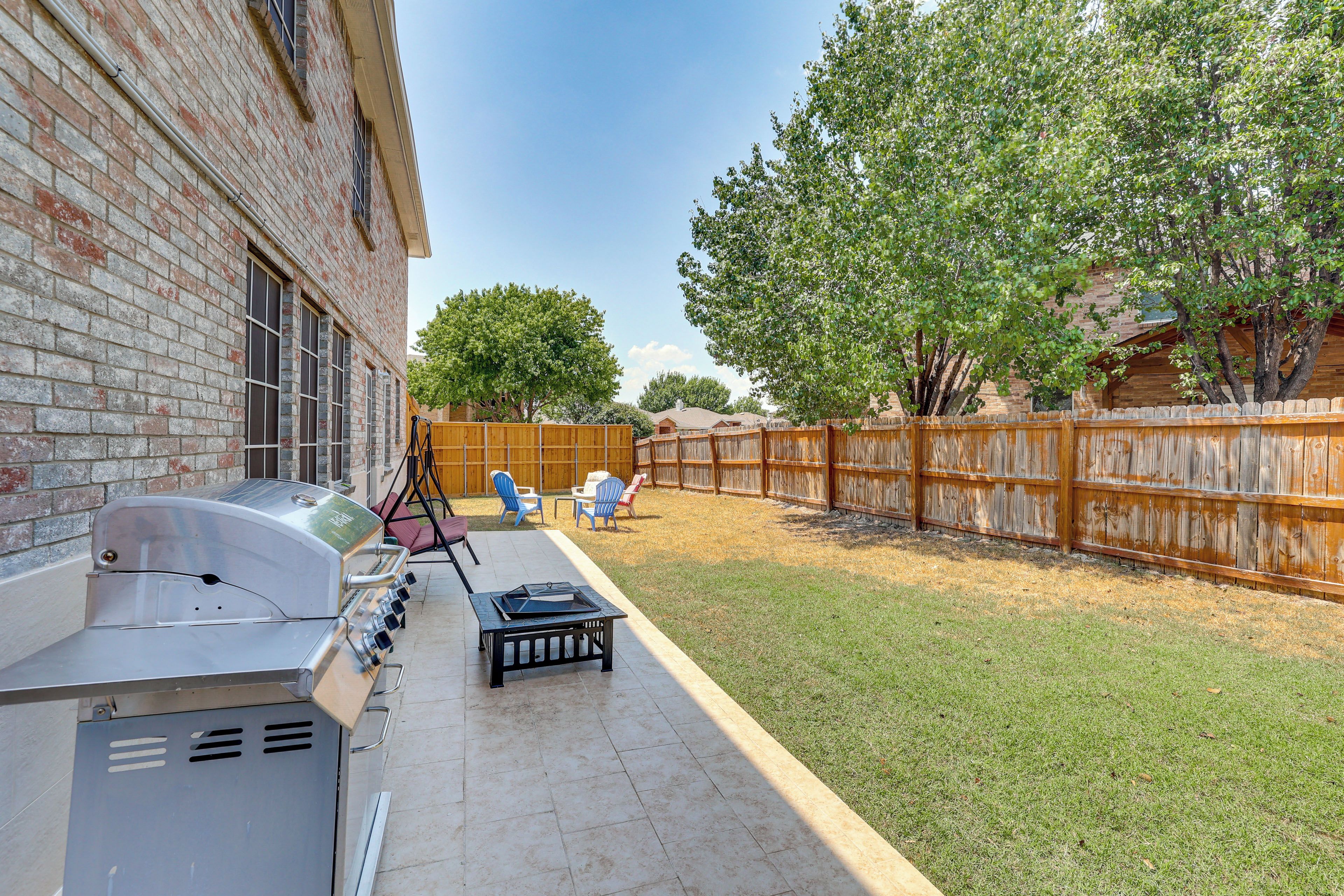 A backyard with a barbecue grill, outdoor seating, and a wooden fence.