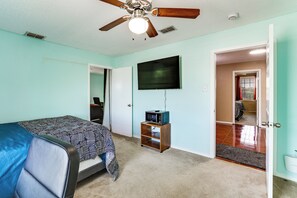 A bedroom with a bed, a ceiling fan, a television, and a door leading to another room. - 9BR Group Getaway Outside Fort Worth (Justin)