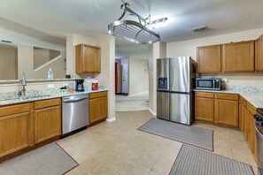 A modern kitchen with stainless steel appliances, wooden cabinets, and a granite countertop. - 9BR Group Getaway Outside Fort Worth (Justin)