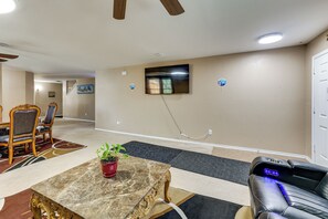 A spacious room with a dining area, a seating area with a massage chair, and a television mounted on the wall. - 9BR Group Getaway Outside Fort Worth (Justin)