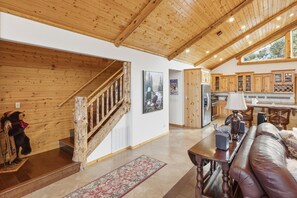 A wooden interior with a staircase, a sofa, and a kitchen area. - Luxury Castle Glen Estate 4 Bedroom! Game Room! Walking Distance to Lake and Trails! (Big Bear Lake)