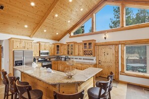 Une cuisine spacieuse avec des meubles en bois, un îlot central et une grande fenêtre donnant sur une terrasse.