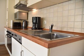 Een keuken met een roestvrijstalen spoelbak, een koffiezetapparaat, een broodrooster en een magnetron.