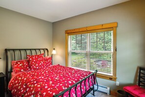 Quarto com cama, mesa de cabeceira, janela com persianas e uma cadeira.