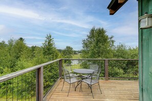 Eine Holzterrasse mit Metallgeländer, zwei Metallstühlen und einem Tisch.