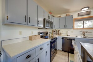 A kitchen with light blue cabinets, a stainless steel microwave, and a Bosch dishwasher.