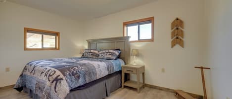 Un dormitorio con cama, mesita de noche, lámpara y un objeto de madera en la pared.