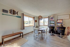 A dining area with a wooden table, white chairs, a bench, and a wall-mounted sign.
