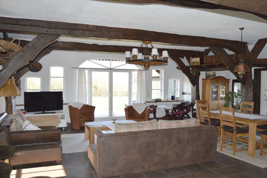 A spacious living room with a television, wooden furniture, and a dining area with a table and chairs.