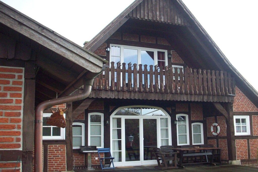 A two-story building with a balcony, a brick wall, and a window.