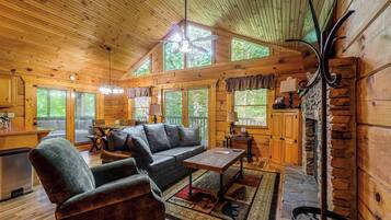 A log cabin interior with a dining area, sofa, and fireplace.