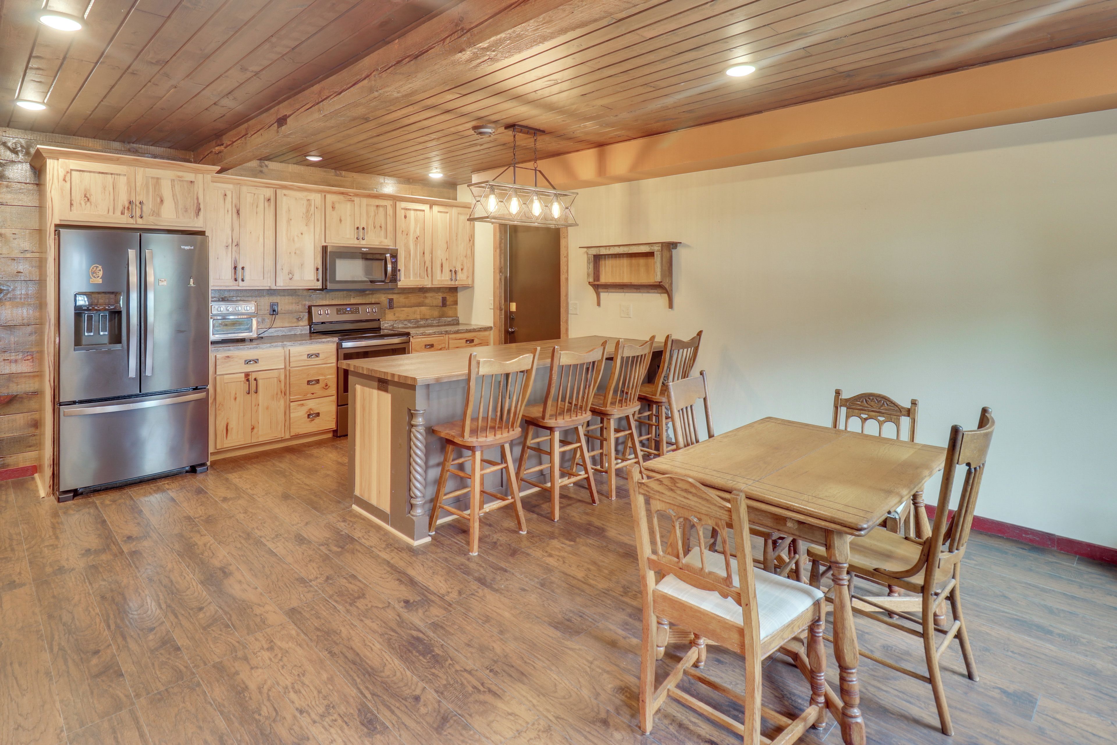 A spacious kitchen with wooden cabinets, stainless steel appliances, and a dining area with wooden chairs and a table.