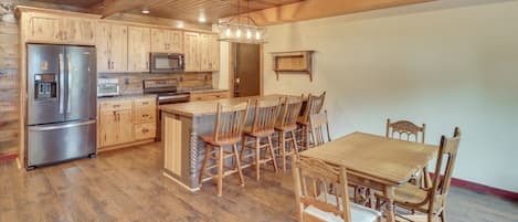 A spacious kitchen with wooden cabinets, stainless steel appliances, and a dining area with wooden chairs and a table.