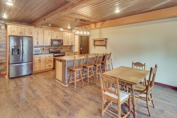 A spacious kitchen with wooden cabinets, stainless steel appliances, and a dining area with wooden chairs and a table.