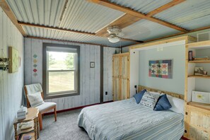 A bedroom with a single bed, a wooden chair, a window, and a bookshelf.
