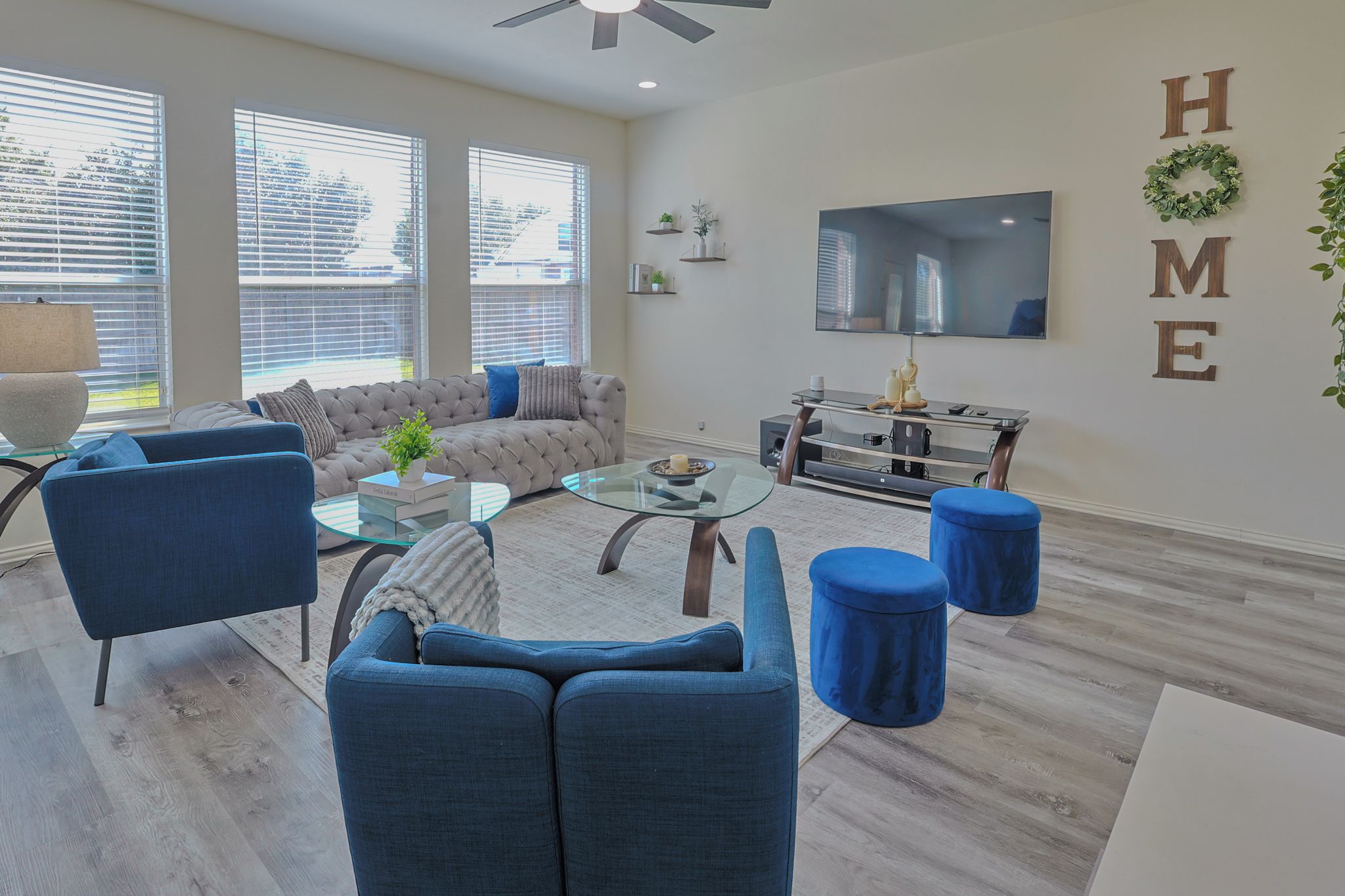 A modern living room with a sectional sofa, a glass coffee table, and a TV mounted on the wall.