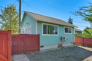 A single-story house with a sloped roof, a front porch, and a red wooden fence. - Quiet South Tacoma Stay Near Shops, Sound & Parks! (Tacoma)