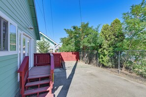 Una propiedad residencial con un deck de madera roja, un camino de grava y una valla de malla de alambre.