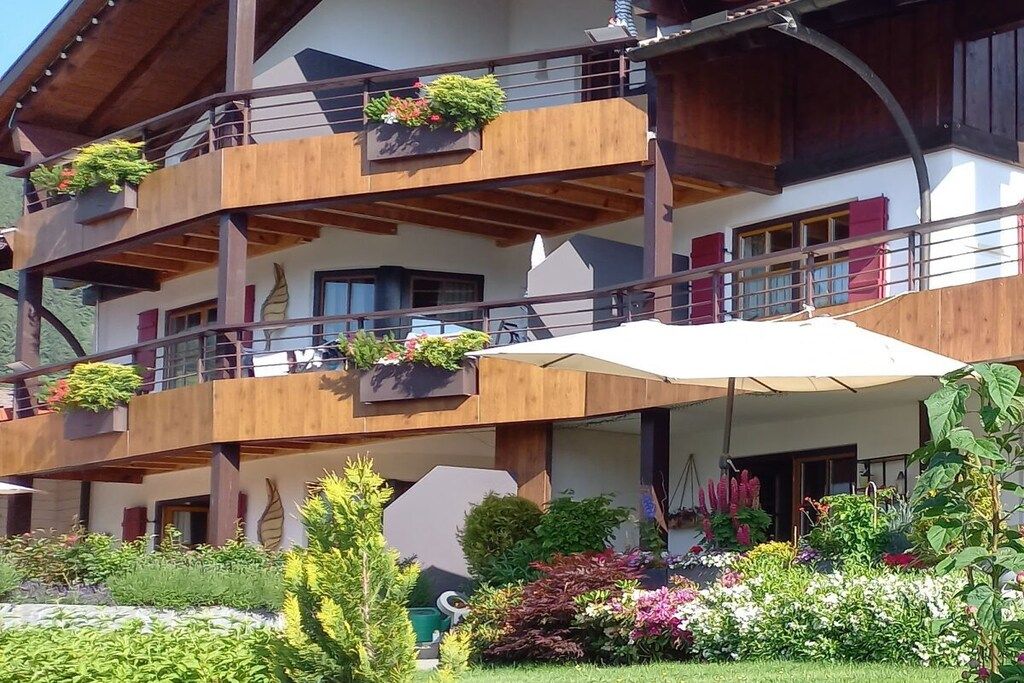 Un edificio de varios pisos con balcones, mobiliario exterior y un jardín.