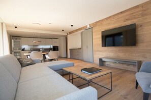 A modern living room with a sofa, a coffee table, and a TV mounted on a wooden wall. - Villa Alpjuwel-Rubihorn (Oberstdorf)