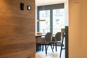A modern dining area with a wooden wall, a table with chairs, and a pendant light. - Villa Alpjuwel-Rubihorn (Oberstdorf)