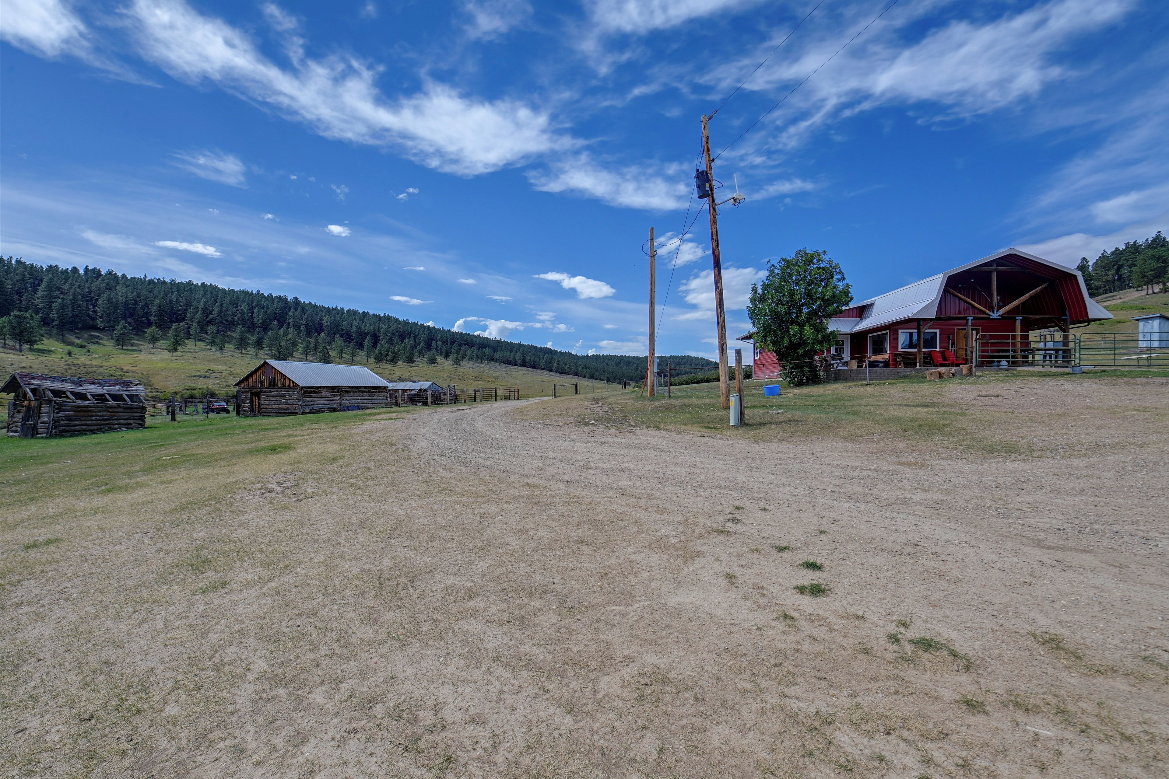 A rural landscape with a dirt road, wooden buildings, and a red barn.