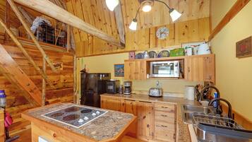 Une cuisine rustique avec des meubles en bois, un réfrigérateur en acier inoxydable, un four à micro-ondes et un plan de travail en granit.