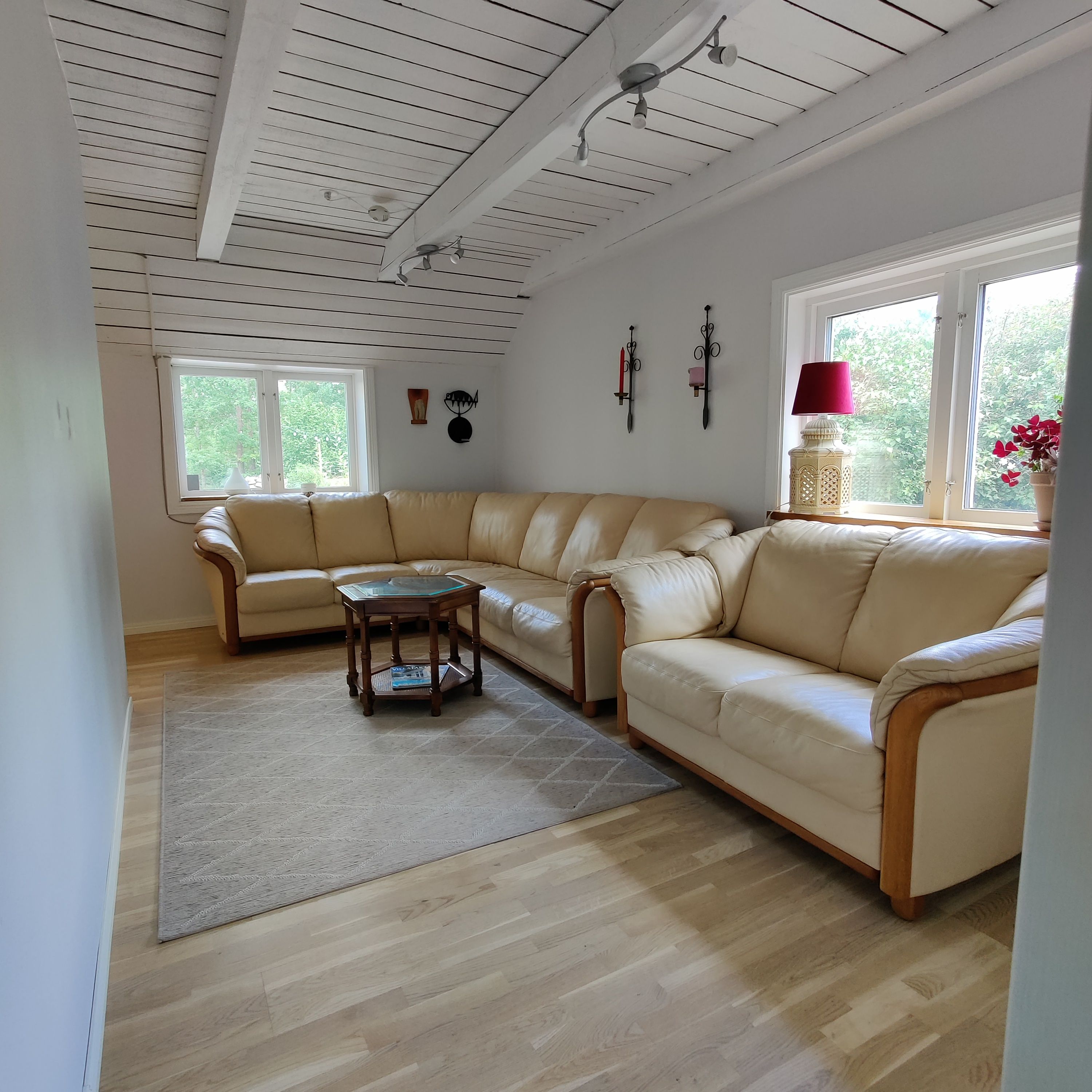 Una sala de estar con un sofá seccional color beige, una mesa de centro de madera y un tapete estampado.