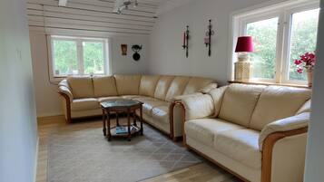 A living room with a beige sectional sofa, a wooden coffee table, and a patterned rug.
