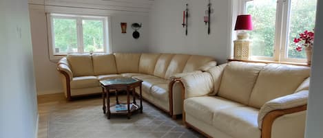 Una sala de estar con un sofá seccional color beige, una mesa de centro de madera y un tapete estampado.